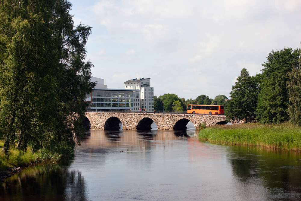 En orange buss åker över en bro